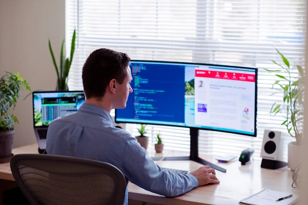 Dual monitors on a desk, showcasing web design in a modern office setting.